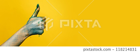 Hand with blue, scaly skin and green dripping paint giving thumbs-up against yellow background. Halloween holiday banner 118214831