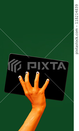 Hand with quirky Halloween themed nails, holding tablet with blank screen against yellow background. News, sales, announcement Hand with quirky Halloween themed nails, holding tablet with blank screen against yellow background. News, sales, announcement 118214839