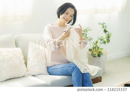 Middle-aged woman knitting in the living room 118215337