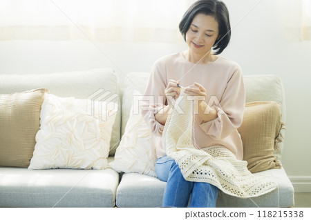 Middle-aged woman knitting in the living room 118215338