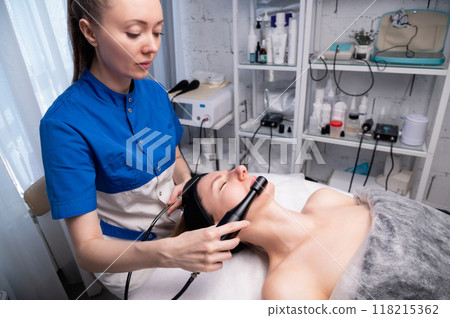 Close-up of massage device in cosmetology room. Lymphatic drainage massage for middle-aged Caucasian white woman Close-up of massage device in cosmetology room. Lymphatic drainage massage for middle-aged Caucasian white woman 118215362