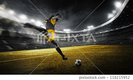 As game near to end, focused on victory soccer player dribbling and kicks ball on green field with full force to score goal under stadium's electric glow. 118215952