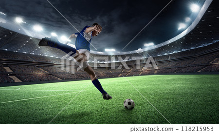 Professional soccer player, forward in yellow and black kit prepares to score, his form silhouetted against golden glow of stadium lights. Professional soccer player, forward in yellow and black kit prepares to score, his form silhouetted against golden glow of stadium lights. 118215953