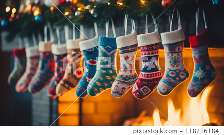 Multi-colored Christmas stockings hang above the fireplace with fire. Waiting for the holiday and gifts. Cozy atmosphere 118216184