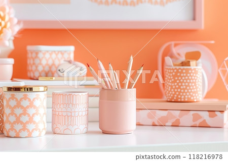 Peach color wall and home office desk with supplies, pencils, pens, boxes, plant pot. Creative stylish minimal workspace. Contemporary flat white work tabletop for product display montage. Blank space 118216978