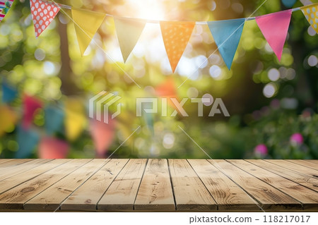 Wooden table desk surface for product display on a blurred festive background with colorful flags, park green leaves bokeh. Outdoor decorated for a festive celebration, garden picnic. Party banner Wooden table desk surface for product display on a blurred festive background with colorful flags, park green leaves bokeh. Outdoor decorated for a festive celebration, garden picnic. Party banner 118217017