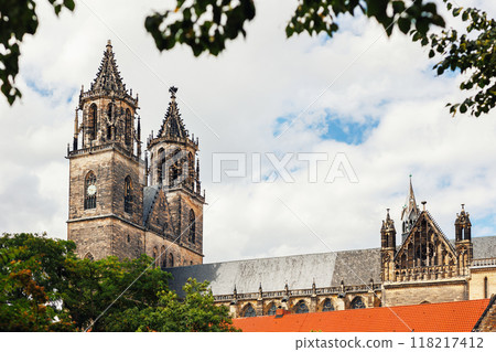 Magdeburg gothic medieval cathedral Dom church slate tile roof and green trees frame against clear blue sky sunny day.  Scenik Saxony-Anhalt sightseeing landmark in Germany 118217412