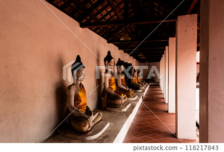 Old buddha statue sitting along the wall. Old buddha statue sitting along the wall. 118217843