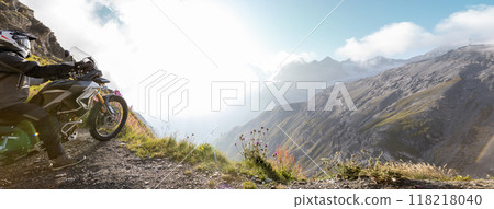 Motorbiker posing on motorbike in Italian Alps during sunrise, dramatic sky. Travel and freedom, outdoor activities 118218040