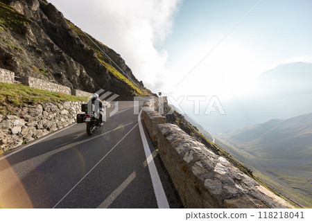 Motorbiker riding in Italian Alps during sunrise, dramatic sky. Travel and freedom, outdoor activities Motorbiker riding in Italian Alps during sunrise, dramatic sky. Travel and freedom, outdoor activities 118218041