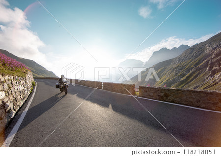 Motorbiker riding in Italian Alps during sunrise, dramatic sky. Travel and freedom, outdoor activities Motorbiker riding in Italian Alps during sunrise, dramatic sky. Travel and freedom, outdoor activities 118218051