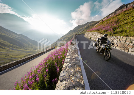 Motorbiker riding in Italian Alps during sunrise, dramatic sky. Travel and freedom, outdoor activities Motorbiker riding in Italian Alps during sunrise, dramatic sky. Travel and freedom, outdoor activities 118218053