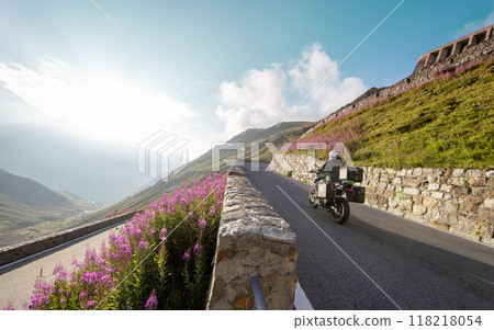 Motorbiker riding in Italian Alps during sunrise, dramatic sky. Travel and freedom, outdoor activities Motorbiker riding in Italian Alps during sunrise, dramatic sky. Travel and freedom, outdoor activities 118218054