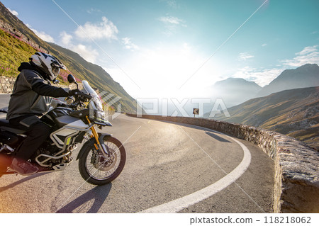 Motorbiker riding in Italian Alps during sunrise, dramatic sky. Travel and freedom, outdoor activities 118218062