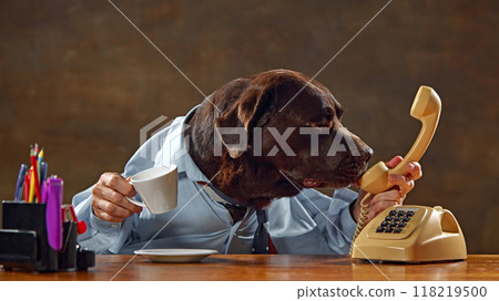 Brown Labrador, dog wearing shirt, sitting at desk, holding phone, and drinking from cup. Conversation with partners 118219500