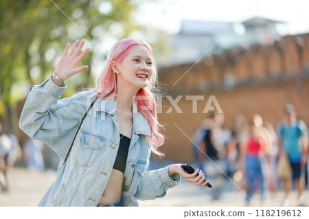A woman with pink hair is waving to people on a street 118219612