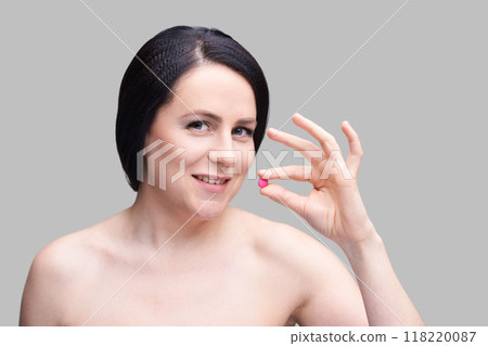 Confident woman holding pink object on gray background - minimalist design 118220087