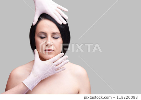 Cosmetic procedure concept with woman's face and hands in gloves on gray 118220088