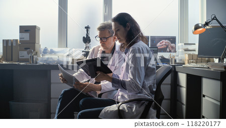 Male and female scientists discuss scientific research, use tablet computer 118220177