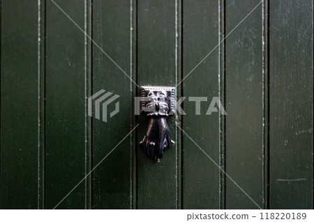 Door knocker on an old wooden green door. Doorknocker. Old-fashioned thing Door knocker on an old wooden green door. Doorknocker. Old-fashioned thing 118220189