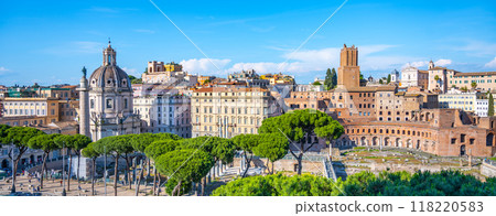 Visitors admire impressive architecture of Trajan Market in Rome, Italy, surrounded by lush greenery and historical buildings. The vibrant atmosphere highlights the rich heritage of the ancient city. 118220583