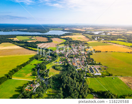 An expansive aerial view showcases the serene rural landscape around Trebon, Czechia, highlighting lush green fields, winding rivers, and small village clusters under a clear blue sky. An expansive aerial view showcases the serene rural landscape around Trebon, Czechia, highlighting lush green fields, winding rivers, and small village clusters under a clear blue sky. 118220588