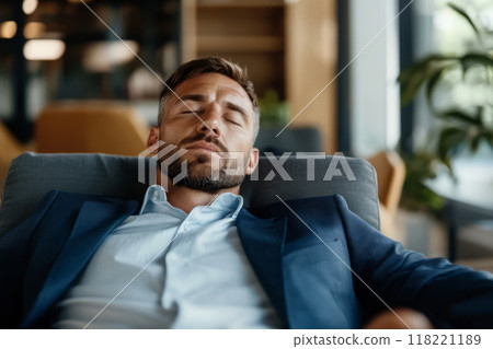 Businessman rests with his eyes closed while sitting in a modern office 118221189