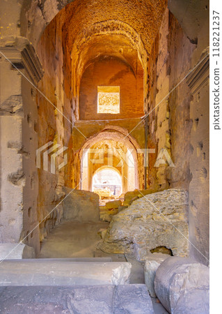 The interior of the Colosseum reveals its haunting beauty with stone arches and weathered walls, showcasing its storied history as visitors explore the iconic monument in Rome. 118221237