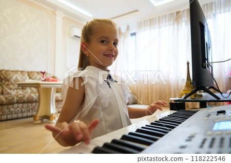 Young girl playing a keyboard in a cozy living room during daytime 118222546