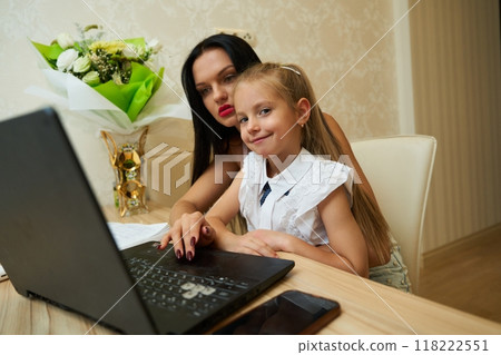 Mother and daughter doing homework together at a modern desk 118222551