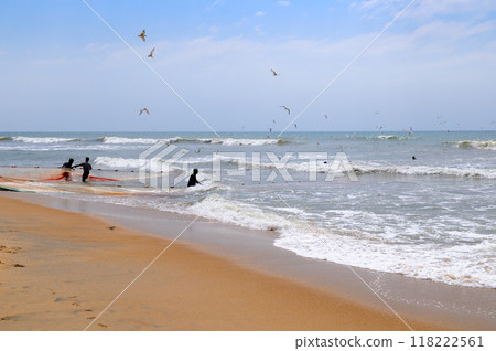 group of men helping fishermen to pull over large fishing net from ocean at beach of south Sri Lanka. group of men helping fishermen to pull over large fishing net from ocean at beach of south Sri Lanka. 118222561