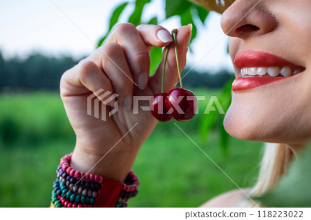 A portrait featuring a smiling woman in profile, holding cherries in her hand 118223022