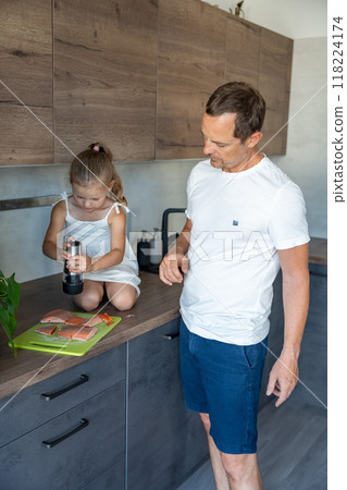 Young father and daughter cooking fish together in home kitchen Young father and daughter cooking fish together in home kitchen 118224174