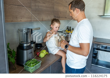 Family with a young father and his little daughter preparing fruit for a healthy juice or smoothie in home kitchen 118224175