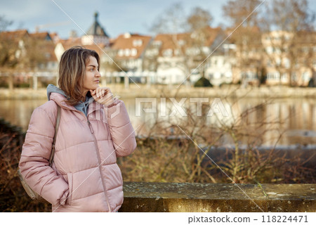 Young beautiful pretty tourist girl in warm hat and coat with backpack walking at cold autumn in Europe city enjoying her travel in Bietigheim-Bissingen, Deutschland. Outdoor portrait of young tourist 118224471