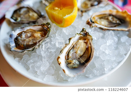 Freshly opened oysters served on ice, garnished with a lemon wedge and a slice of orange 118224607