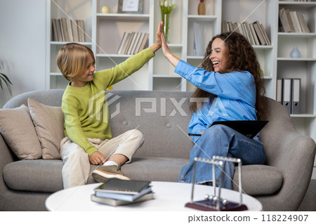Long-haired young woman talking to a blonde boy, both looking contented 118224907