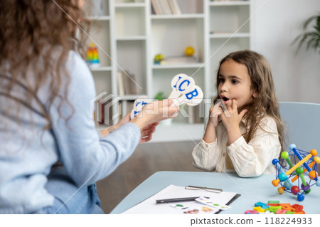 Speech therapist showing letters to a girl while having a training session 118224933