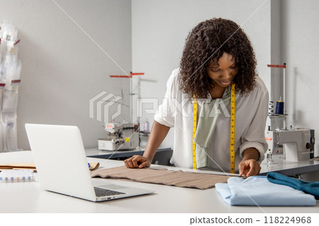 Woman fashion designer sewing clothing with online sketches on laptop 118224968