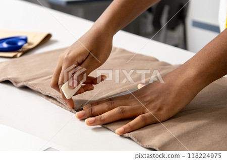 Dressmaker working on clothing projects using material in a professional studio 118224975