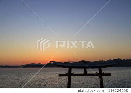 A torii gate standing in the sea and sea mist flowing through the Seto Inland Sea at dawn 118224998