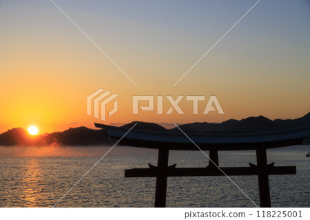Sea mist flowing through the Seto Inland Sea at dawn, a torii gate standing in the sea, and the rising sun Sea mist flowing through the Seto Inland Sea at dawn, a torii gate standing in the sea, and the rising sun 118225001