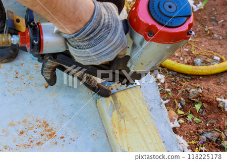 Pneumatic air hammer is used to nail wooden beams to concrete during construction of new house Pneumatic air hammer is used to nail wooden beams to concrete during construction of new house 118225178