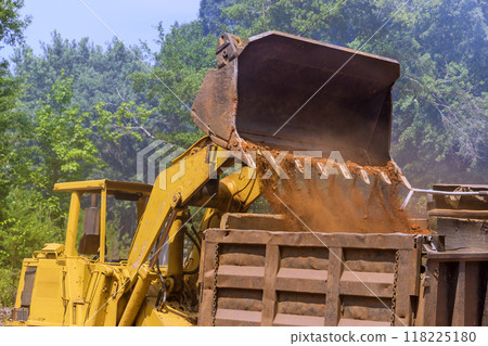 Bucket of bulldozer fills with earth in an industrial zone 118225180