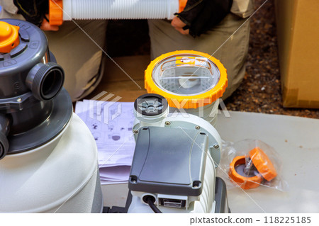 Maintenance worker assembles sand filter system tank cleaning equipment for swimming pool 118225185