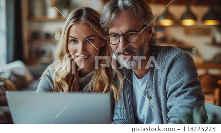 A middle-aged man and a young woman, both smiling are working together on a laptop. 118225223