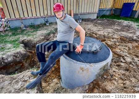 Worker assembled second chamber of septic tank from concrete rings and sat down to rest on manhole cover. 118225939