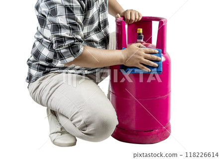 A man is kneeling down next to a pink gas cylinder A man is kneeling down next to a pink gas cylinder 118226614