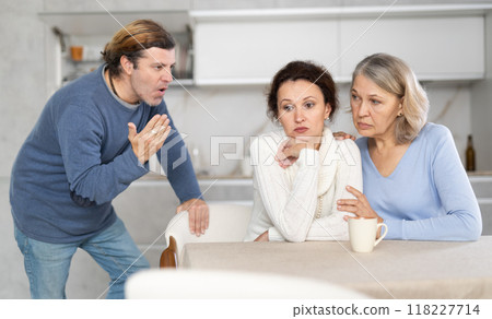 Old woman comforts her daughter while her husband yells at her 118227714