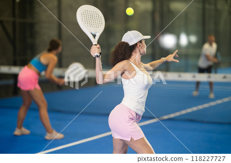 Woman playing padel on open court on summer day. Sport and active lifestyle concept 118227727